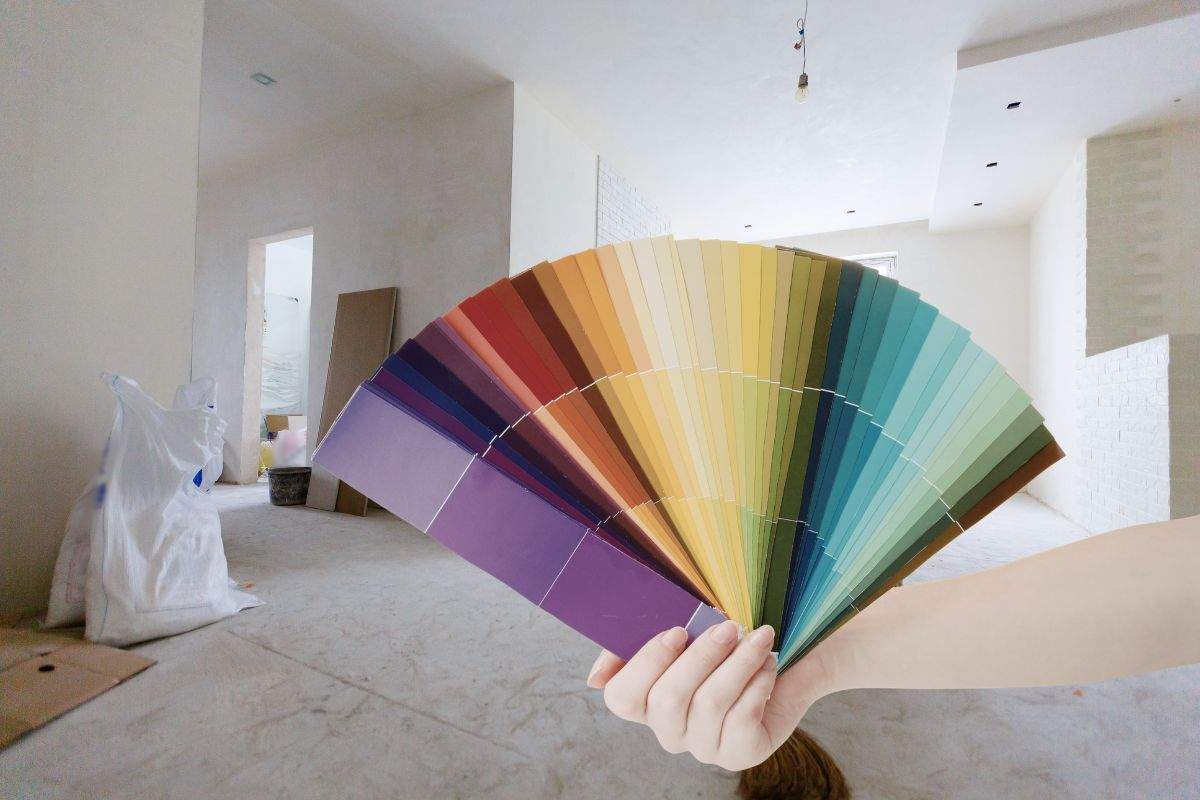 sfondo di una casa in ristrutturazione e mano che mantiene palette di colori