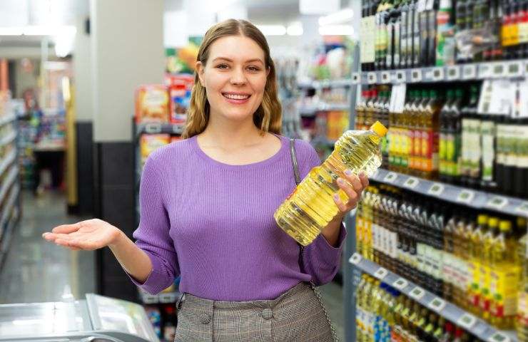 donna con bottiglia di olio in mano al supermercato